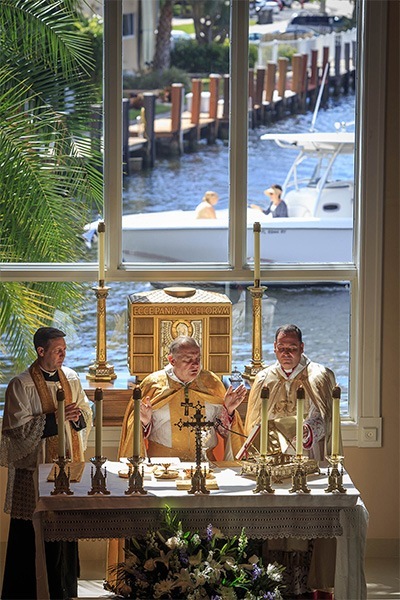 As pleasure boats cruise behind them, Archbishop Thomas Wenski, center, Chorbishop Michael Thomas, right, and Father Richard Vigoa, celebrate Mass in the Maronite rite at Heart of Jesus Church in Fort Lauderdale.