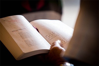 A parishioner reads the Gospel from the Maronite missal, which has one side in English and the other in Syriac.