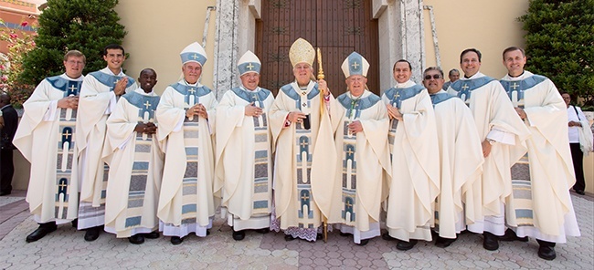 The three new priests pose for the official photo after the ordination Mass. Father Ivan Rodriguez is second from left, Father Fenly Saint-Jean is third from left, and Father Matias Hualpa is fourth from the right. With them are their seminary rectors, Father Emanuele De Nigris of Redemptoris Mater, Msgr. Roberto Garza of St. John Vianney, and Msgr. David Toups of St. Vincent de Paul, along with Archbishop Thomas Wenski, Auxiliary Bishop Peter Baldacchino, Archbishop Emeritus John C. Favalora and Bishop Fernando Isern, Emeritus of Pueblo, Colo.