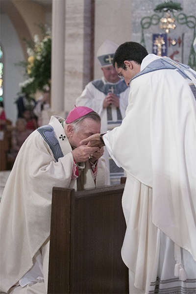 Archbishop Thomas Wenski kisses the anointed hands of newly-ordained Father Ivan Rodriguez.