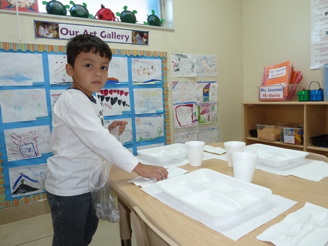 Justin Calix, 5 años, organiza la mesa de su clase de pre-k para la hora del almuerzo.