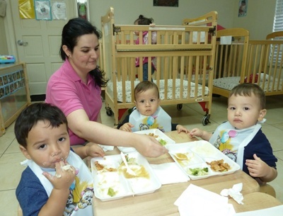 Odelay Bermúdez, maestra de cuidado infantil en Centro Mater hace 13 años, le da de comer a los bebés- de izquierda a derecha: Valentin Rodríguez, Aithan Rivera y Nathan Herrera.