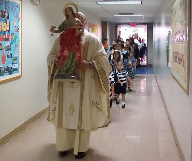 Father Marcos Somarriba, pastor of St. Agatha Parish, leads the procession of students with a new statue of St. Agatha that was blessed and placed in the school building.