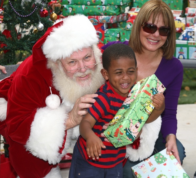 Kentrell Smith, 4, is ecstatic as he receives a Christmas gift from Santa Claus. Looking on is Telemundo 51 anchor Maria Montoya.