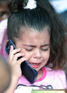 Alexa Rodriguez, 3, cries because she received a "Dream Doll" instead of the bike and scooter she asked for. Her mother, who was present at the event, gave her the phone to speak to her father, who said he would arrange for Santa to bring her the toys she wanted.