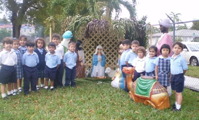 Students from Sts. Peter & Paul School in Miami pose with the Nativity scene they helped decorate in the schools garden.